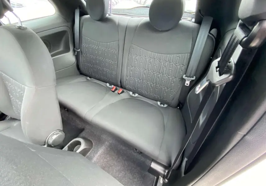 Vue intérieure de la banquette arrière noire de la Fiat 500 2024 avec appuie-têtes ronds et ceintures visibles.
