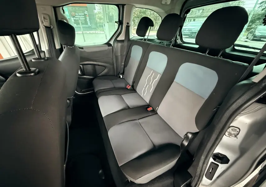 Vue intérieure côté droit montrant la banquette arrière trois places avec tissu noir et gris du Peugeot Partner Tepee gris.
