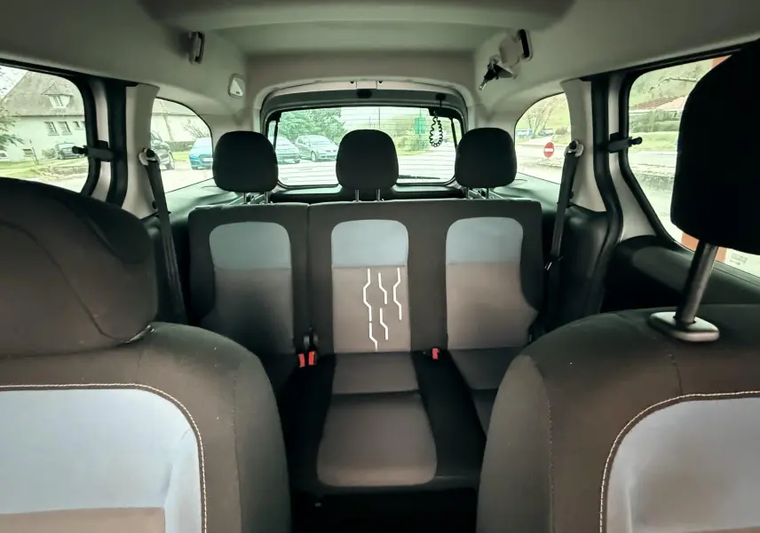 Vue intérieure arrière du Peugeot Partner Tepee 2014, sièges tissu noir et gris avec motifs blancs au centre.