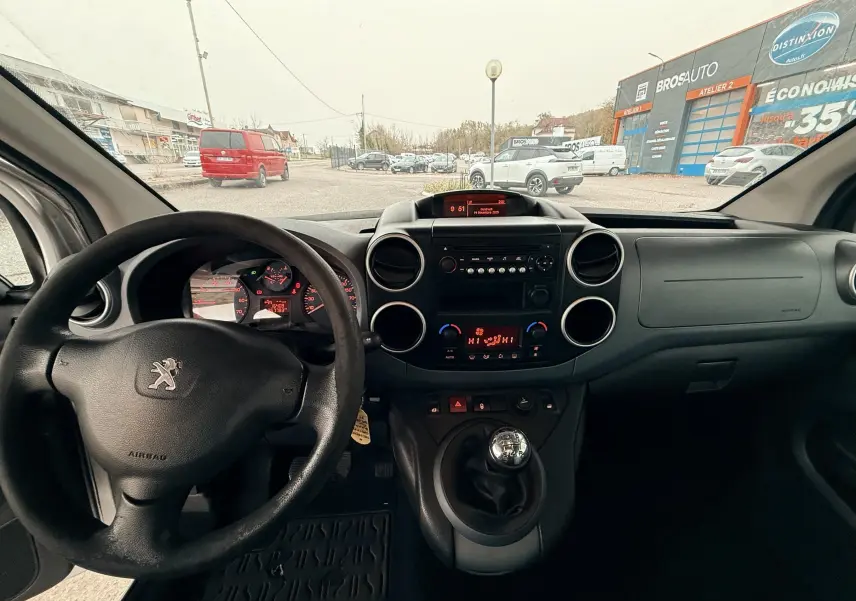 Vue intérieure avant du Peugeot Partner Tepee gris, montrant le volant, tableau de bord et levier de vitesses manuel.