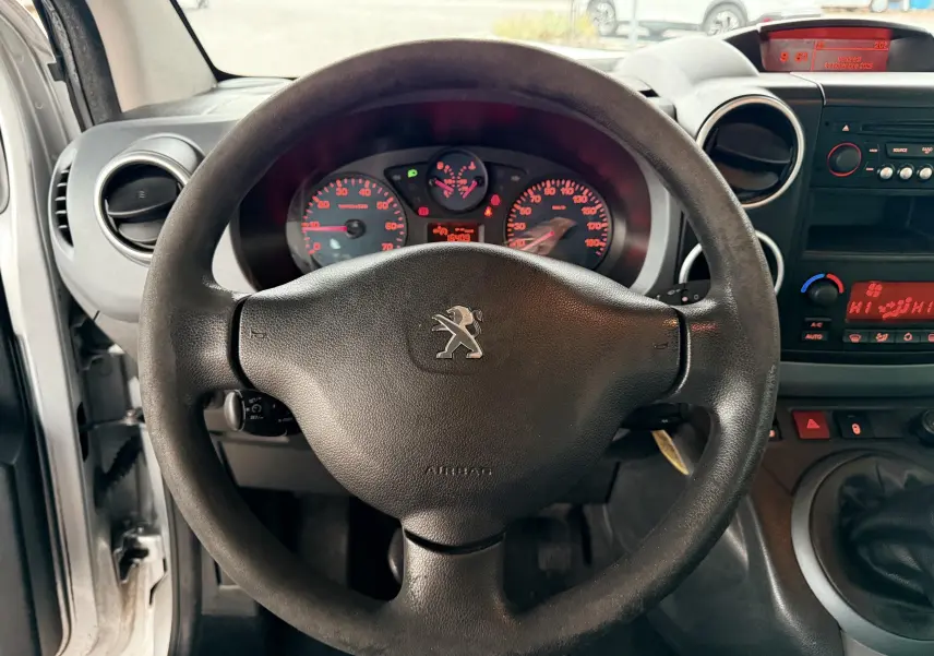 Vue intérieure centrée sur le volant noir de la Peugeot Partner Tepee 2014 avec tableau de bord et console gris foncé.