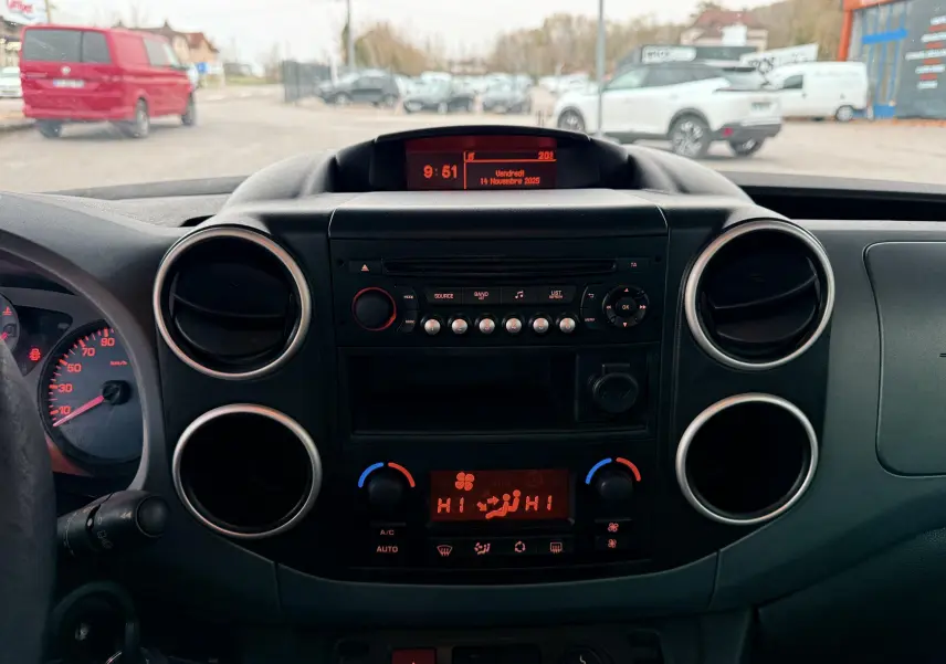 Tableau de bord noir du Peugeot Partner Tepee gris, vue frontale centrée sur la console et les aérateurs ronds.