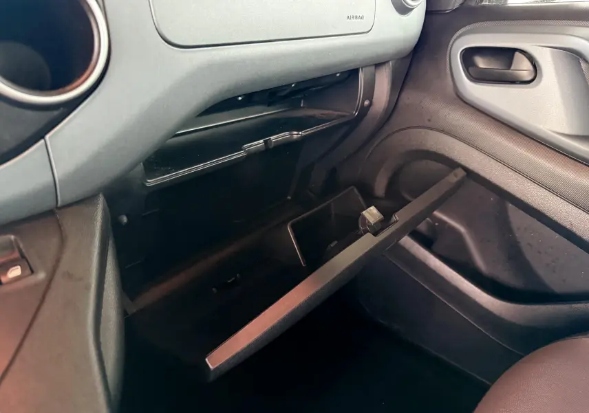 Intérieur du Peugeot Partner Tepee 2014, vue côté passager sur la boîte à gants ouverte et tableau de bord gris.