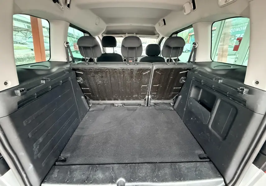 Vue depuis le coffre du Peugeot Partner Tepee gris, montrant l'espace de chargement et les dossiers des sièges arrière relevés.