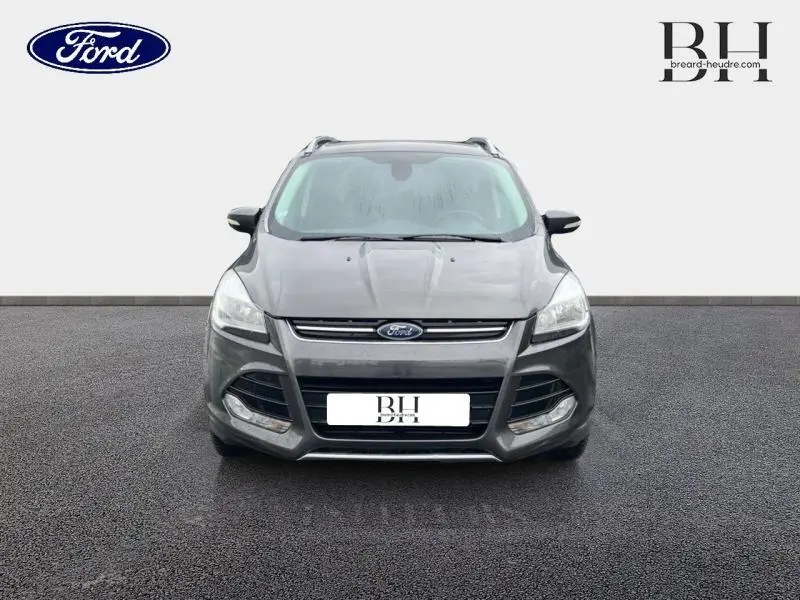Vue de face d'un Ford Kuga gris Magnetic 2015 avec calandre chromée et phares halogènes visibles.