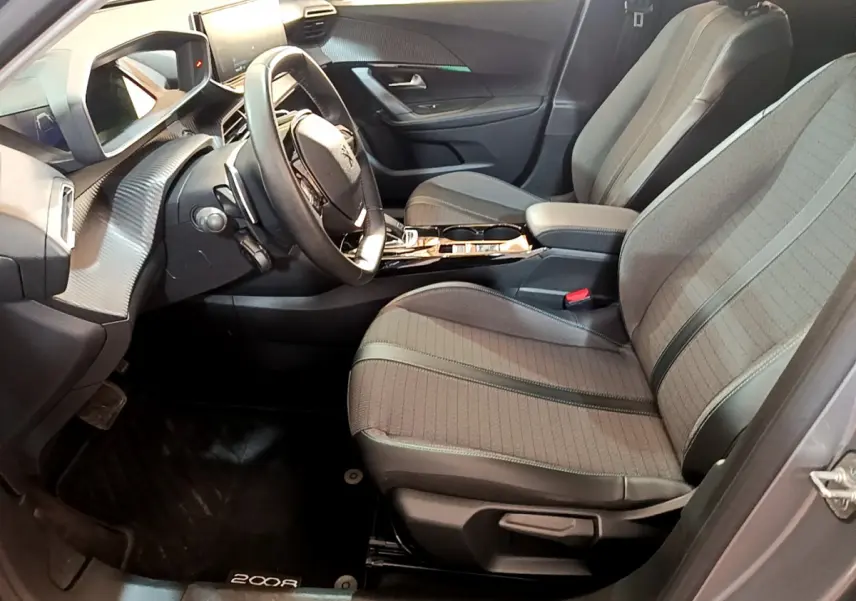 Vue intérieure côté conducteur du Peugeot 2008 gris clair, avec sièges tissu, volant cuir multifonctions et tableau de bord digital.