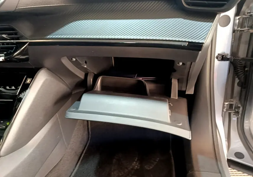 Vue intérieure côté passager du Peugeot 2008 gris clair 2021, boîte à gants ouverte sous tableau de bord.