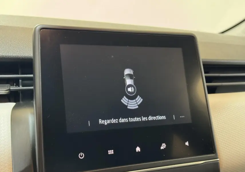 Écran tactile intérieur de la Renault Clio Business blanc, affichant l'alerte de détection d'obstacles au stationnement.