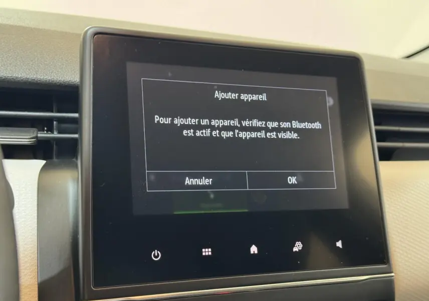 Écran tactile central du tableau de bord de la Renault Clio Business blanc, affichant un message Bluetooth.
