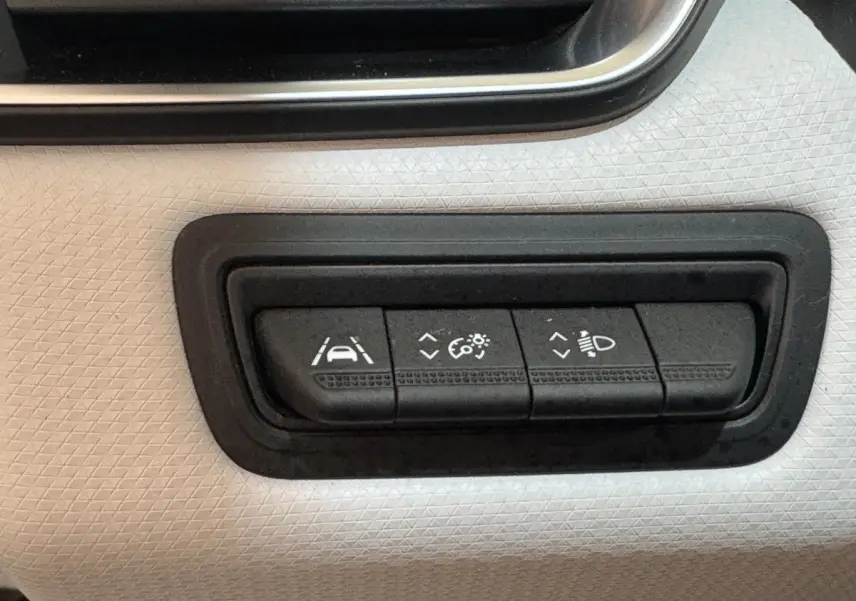Gros plan sur les commandes d'assistance à la conduite sur panneau blanc texturé intérieur Renault Clio Business TCe 100 GPL 2023.