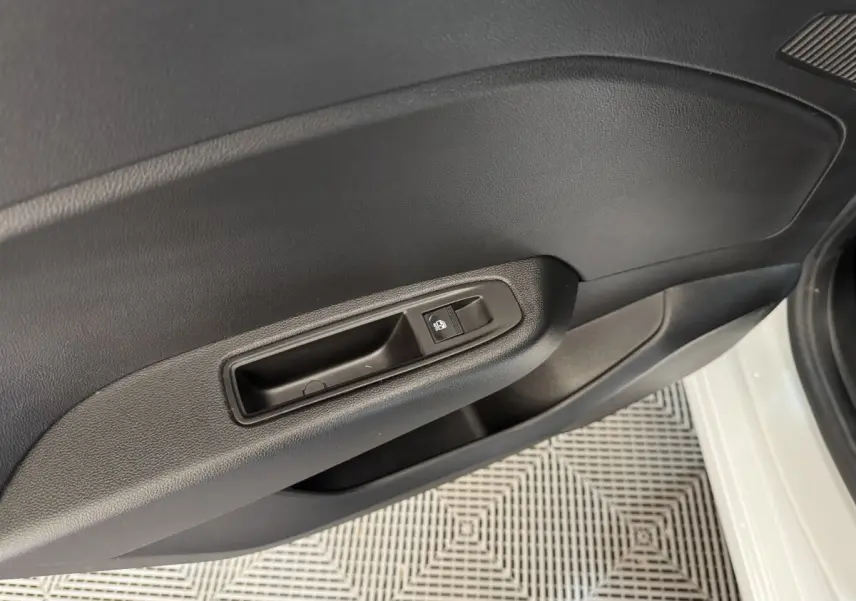 Détail de la porte intérieure côté conducteur d'une Renault Clio Business blanche, avec commande de vitre électrique.