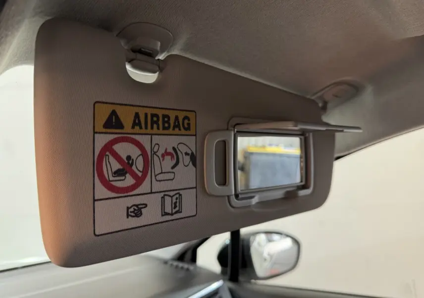 Détail du pare-soleil côté conducteur avec miroir et avertissement airbag dans Renault Clio blanc 2023.