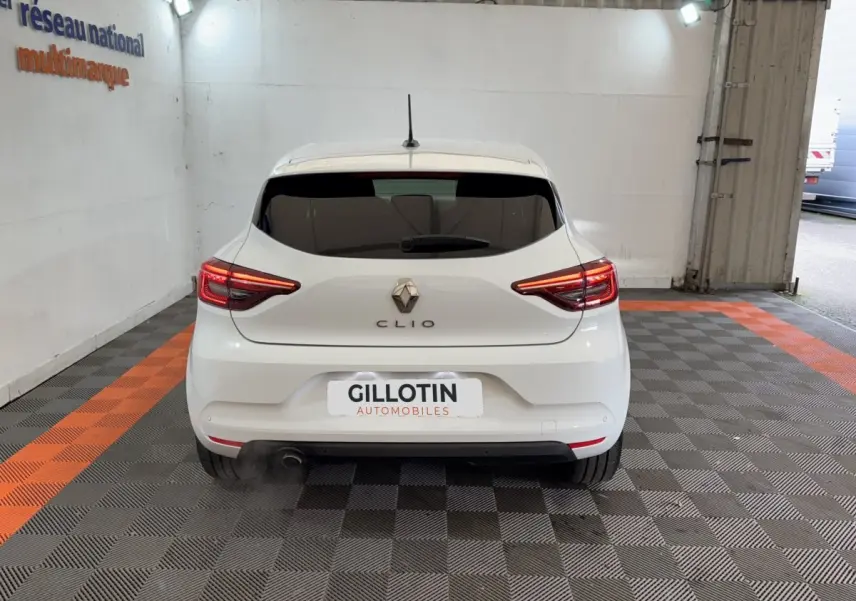 Vue arrière d'une Renault Clio blanche 2023 avec feux LED allumés dans un garage.