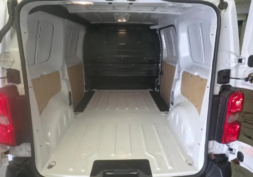 Vue arrière du fourgon blanc Opel Vivaro 2025, montrant l'espace de chargement vide avec parois partiellement protégées.