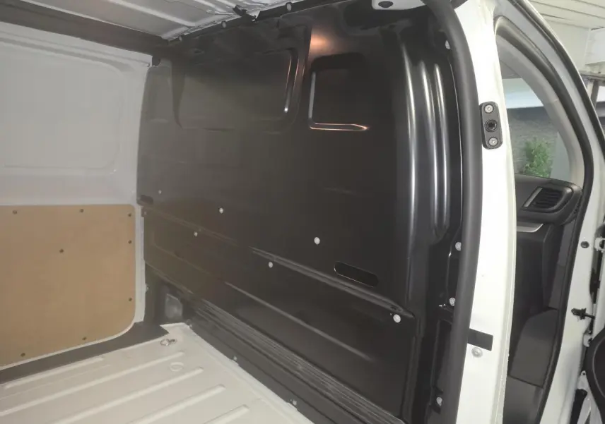 Vue intérieure côté droit du compartiment de chargement blanc de l’Opel Vivaro 2025 avec cloison tôlée noire.