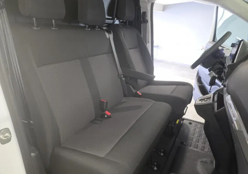 Vue intérieure côté conducteur de l'Opel Vivaro blanc 2025, montrant la banquette tissu bi-ton noir et gris et le tableau de bord.