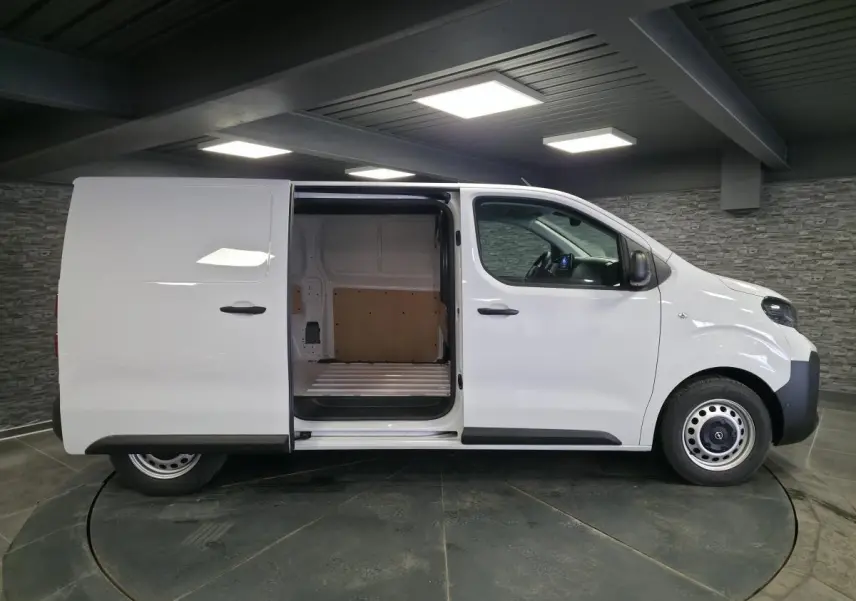 Profil droit d’un utilitaire Opel Vivaro blanc 2025 avec porte latérale coulissante ouverte montrant l’espace de chargement.