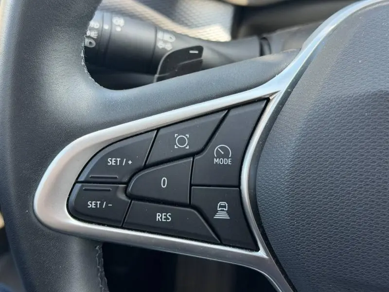 Gros plan sur les commandes du volant du Renault Arkana gris métallisé, avec boutons de régulateur et mode de conduite.