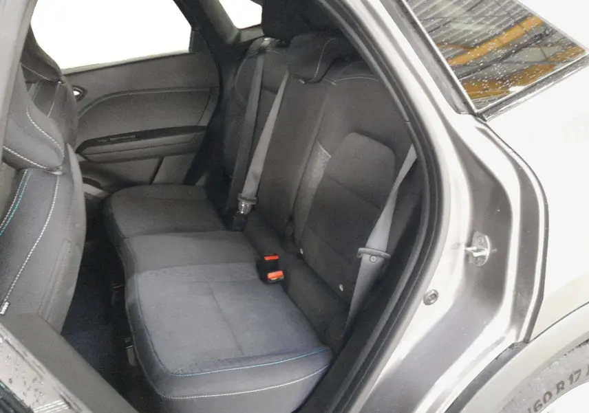 Vue intérieure côté arrière droit du Renault Symbioz gris Cassiopée, montrant les sièges arrière en tissu avec surpiqûres bleues.