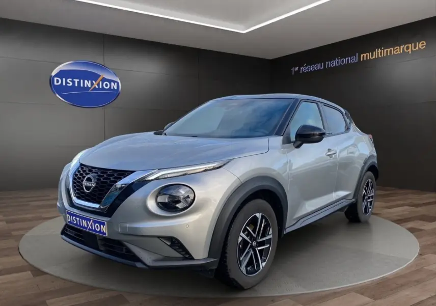 Nissan Juke gris clair en 3/4 avant droit, avec jantes alliage noires et toit noir contrasté.