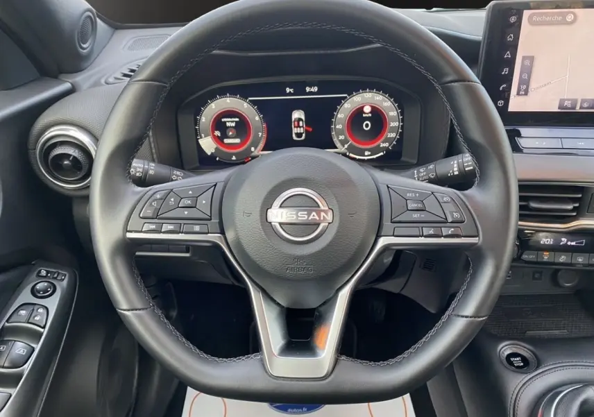 Vue intérieure centrée sur le volant cuir et alu du Nissan Juke 2025 avec tableau de bord numérique et écran tactile.