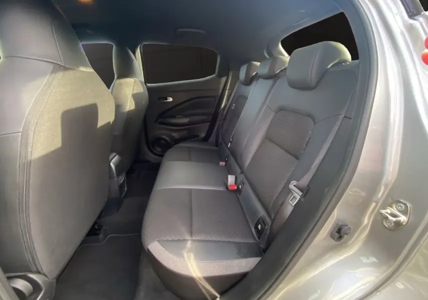 Vue intérieure arrière côté droit du Nissan Juke gris clair, montrant la banquette et les sièges avant.