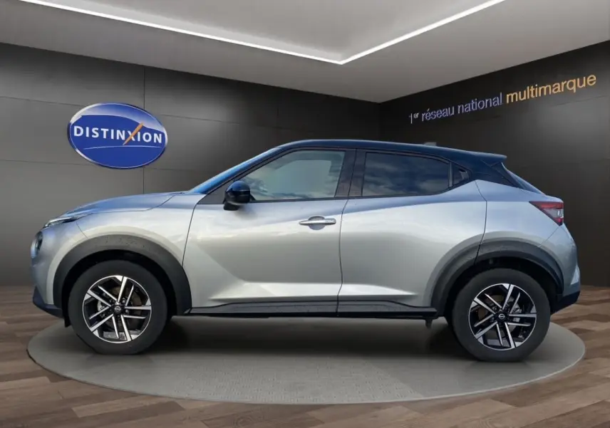Vue de profil côté gauche d'un Nissan Juke gris clair avec jantes alliage et arches de roues noires.