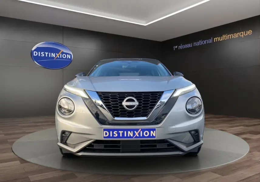 Vue frontale d'un Nissan Juke gris clair 2025 avec calandre noire et logo Nissan bien visible.