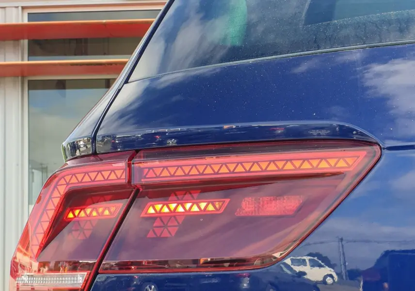Gros plan sur le feu arrière droit d'un Volkswagen Tiguan bleu Atlantique métallisé, avec le logo Tiguan visible.