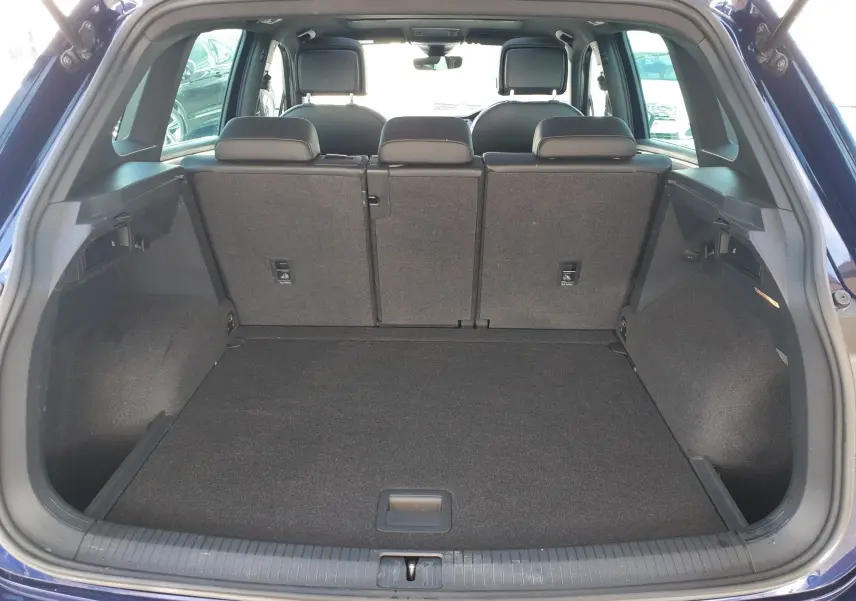 Vue arrière du coffre spacieux d'un Volkswagen Tiguan bleu Atlantique métallisé avec sièges arrière relevés.