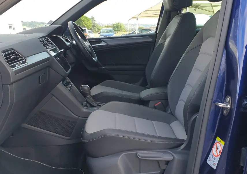 Intérieur côté conducteur d'un Volkswagen Tiguan bleu Atlantique 2018, sièges tissu gris et toit ouvrant panoramique visible.