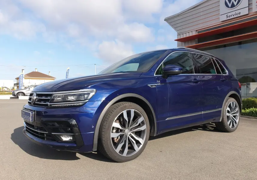 Volkswagen Tiguan bleu Atlantique métallisé vu en 3/4 avant droit, avec jantes alliage et calandre caractéristique.