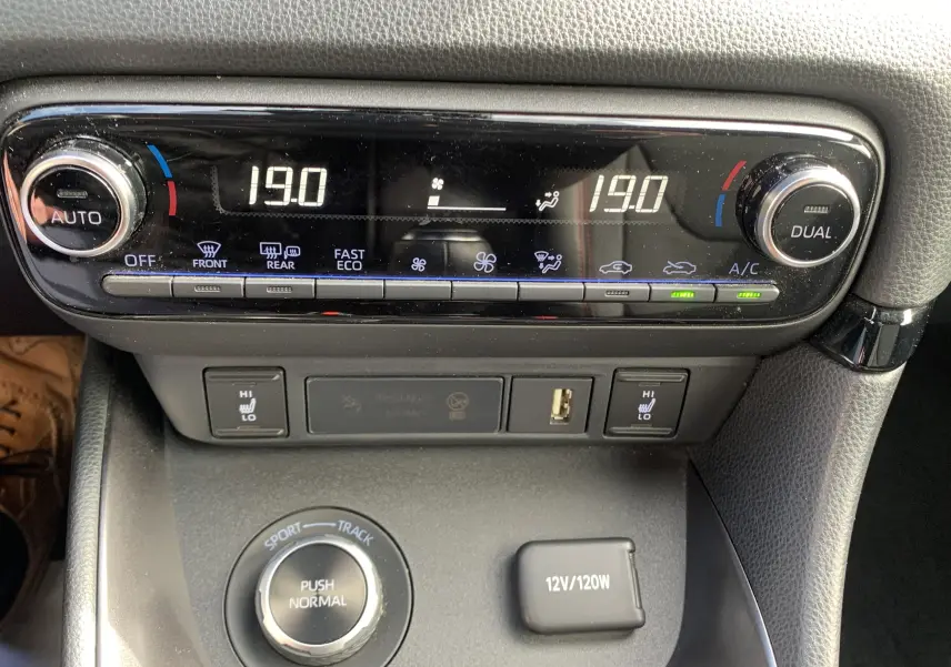 Gros plan sur la console centrale de la Toyota Yaris 2021, montrant la climatisation digitale et les commandes de modes de conduite.