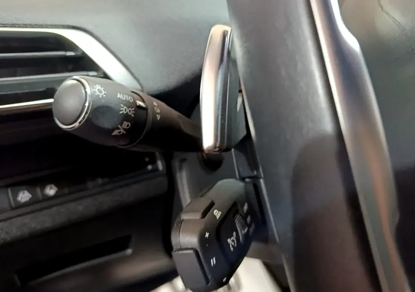Gros plan sur la commande des phares et régulateur de vitesse au volant cuir du Peugeot 3008 PureTech 130 GT.