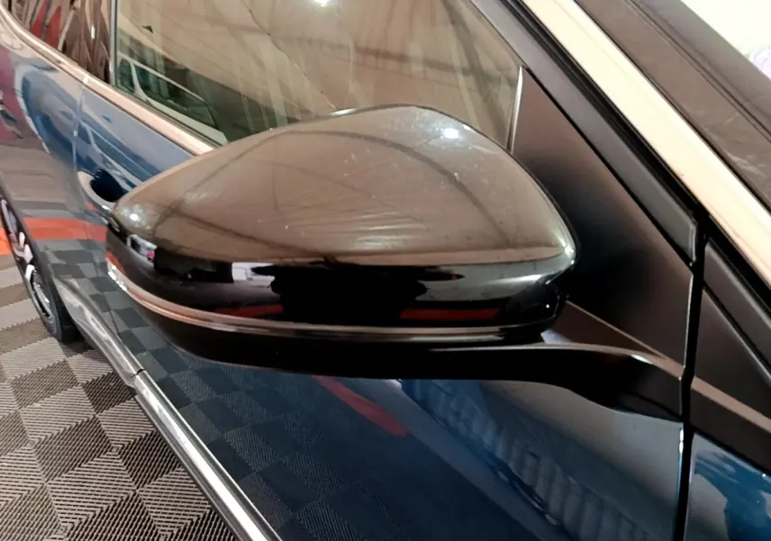 Gros plan sur le rétroviseur noir côté gauche d’un Peugeot 3008 bleu, avec reflet sur la carrosserie.