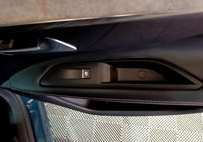 Détail de la porte côté gauche du Peugeot 3008 bleu, montrant la commande de lève-vitre et la poignée intérieure.