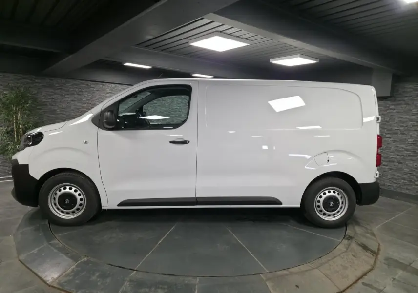 Opel Vivaro blanc vu de profil côté gauche, fourgon utilitaire avec roues tôles et poignées noires.
