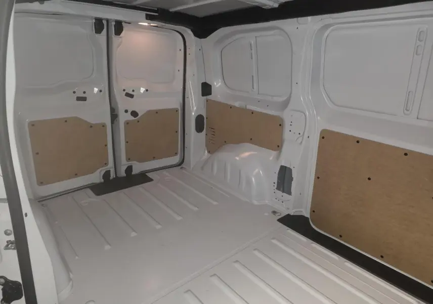 Vue intérieure arrière du fourgon Opel Vivaro blanc 2025, montrant l'espace de chargement avec panneaux de protection en bois.