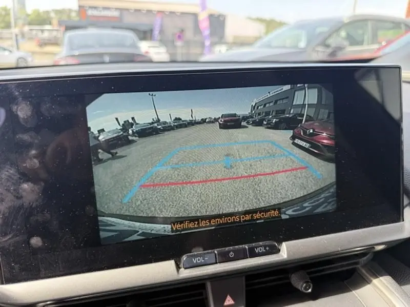Vue arrière en caméra de recul du Toyota C-HR Hybride bleu persan 2024, avec lignes d’aide au stationnement visibles.