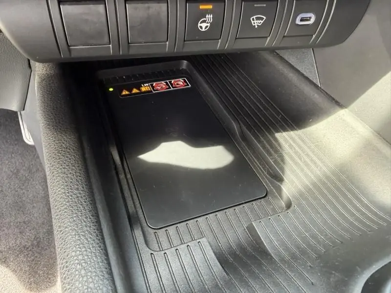 Détail de la console centrale du Toyota C-HR Hybride 2024, montrant le chargeur sans fil et les boutons de commande en noir.