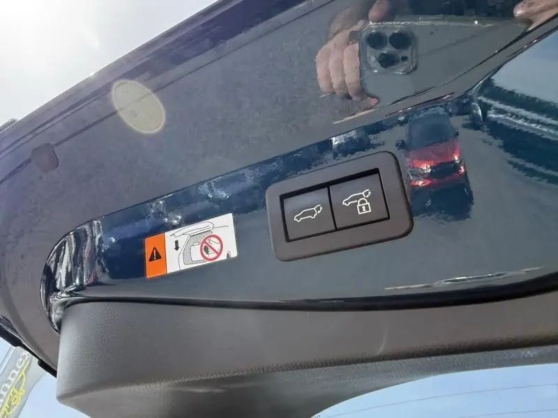 Détail intérieur du hayon bleu persan du Toyota C-HR Hybride 2024 avec boutons d’ouverture et verrouillage du coffre.