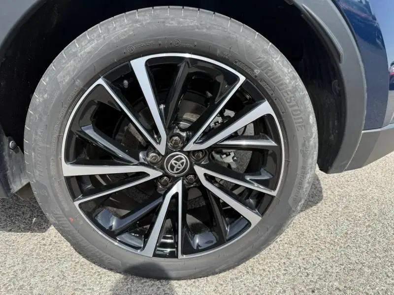 Gros plan sur la roue avant droite du Toyota C-HR Hybride 2024 bleu persan avec jante alliage noire et argentée.