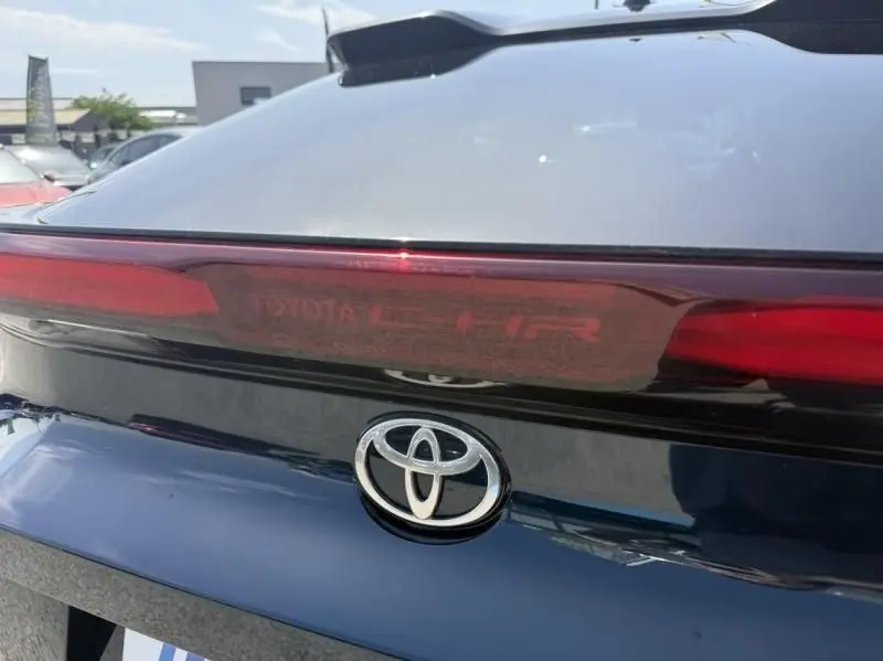 Gros plan sur l'arrière bleu persan du Toyota C-HR Hybride 2024, mettant en valeur le logo Toyota et le bandeau lumineux.