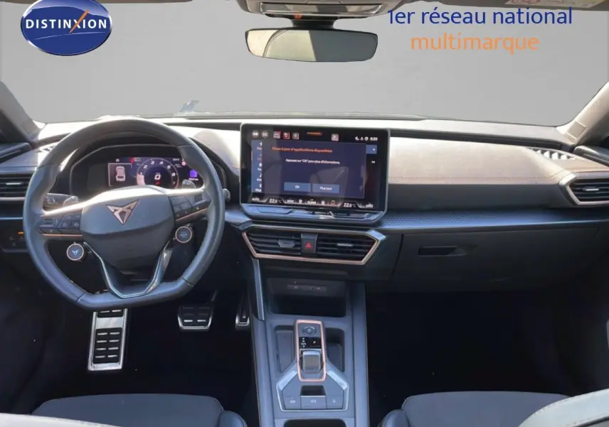 Vue intérieure avant du tableau de bord et volant cuir noir du CUPRA Leon 1.5 eTSI 150CH DSG, avec écran tactile central.