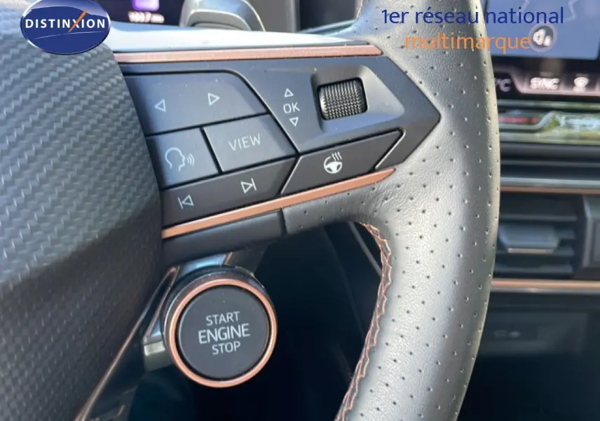 Gros plan sur le volant en cuir perforé de la CUPRA Leon bleu Fjord, avec bouton Start Engine Stop et commandes intégrées.