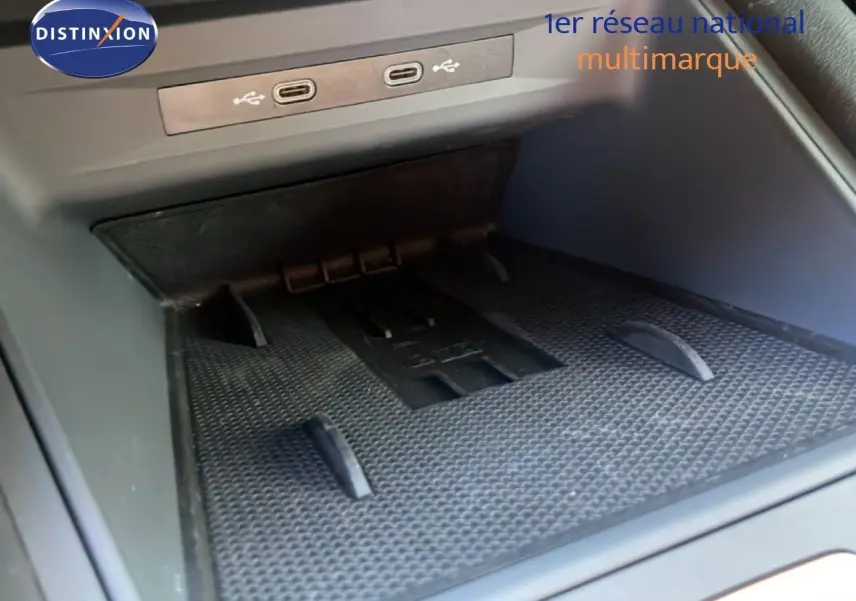 Gros plan sur la console centrale intérieure du CUPRA Leon 1.5 eTSI 150CH DSG avec ports USB et espace de rangement.