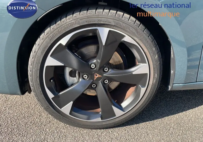 Gros plan sur la roue avant gauche d'une CUPRA Leon bleu Fjord avec jante alliage bicolore et logo CUPRA central.