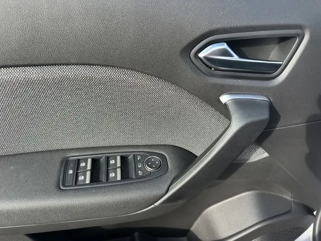 Vue intérieure côté gauche de la porte avant d’un Renault Captur gris foncé avec commandes électriques des vitres et poignée argentée.