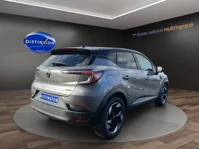 Vue 3/4 arrière droite d'un Renault Captur gris foncé hybride, avec jantes noires et feux LED distinctifs.