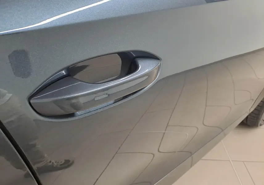 Poignée de porte côté gauche de la CUPRA Formentor 1.4 e-HYBRID 245 gris magnétique avec reflet du sol carrelé.